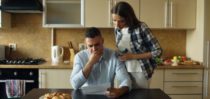 Paar in der Küche: Mann mit Unterlagen, Frau reicht ihm eine Tasse